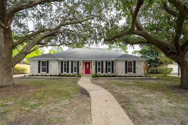 ranch-style home featuring brick siding and roof with shingles