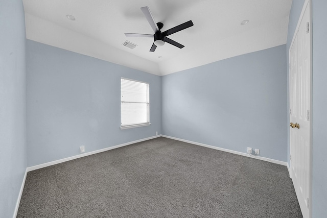 empty room featuring visible vents, vaulted ceiling, baseboards, and dark colored carpet