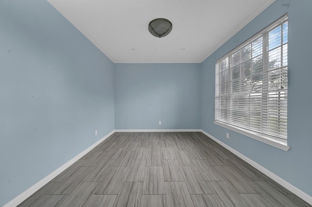 unfurnished room with baseboards, crown molding, and wood finish floors