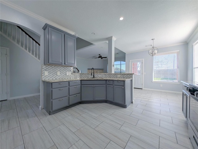 kitchen featuring a sink, backsplash, gray cabinetry, and a peninsula