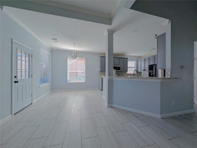 kitchen featuring crown molding, tasteful backsplash, gray cabinets, a healthy amount of sunlight, and a peninsula