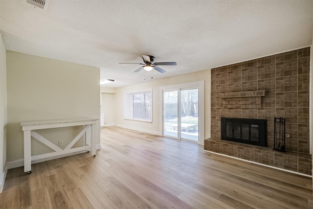 19823 Burle Oak Dr, Humble, TX 77346 - unfurnished living room featuring a ceiling fan, wood finished floors, visible vents, a fireplace, and a textured ceiling