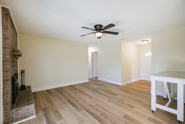 19823 Burle Oak Dr, Humble, TX 77346 - unfurnished living room with a ceiling fan, a textured ceiling, a fireplace, light wood finished floors, and baseboards