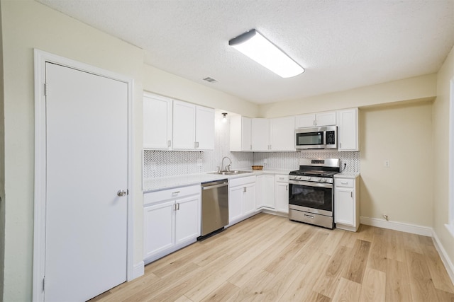 19823 Burle Oak Dr, Humble, TX 77346 - kitchen featuring a sink, light countertops, appliances with stainless steel finishes, white cabinetry, and tasteful backsplash