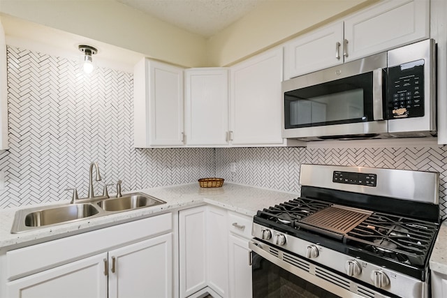 kitchen featuring a sink, white cabinets, tasteful backsplash, and stainless steel appliances