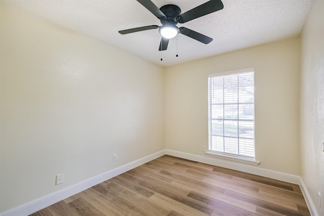 spare room with baseboards, a textured ceiling, and light wood finished floors