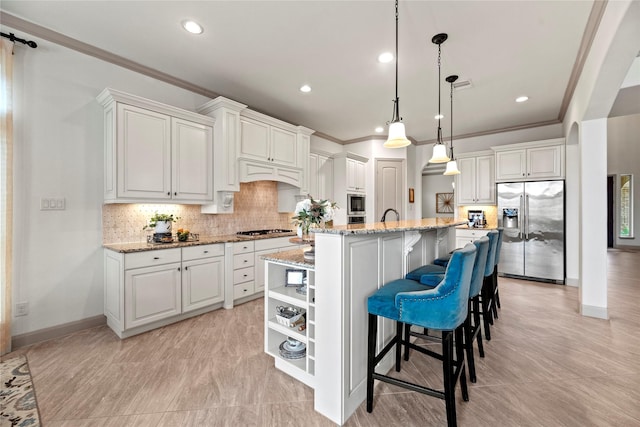 kitchen featuring a center island with sink, stainless steel appliances, hanging light fixtures, white cabinets, and light stone countertops