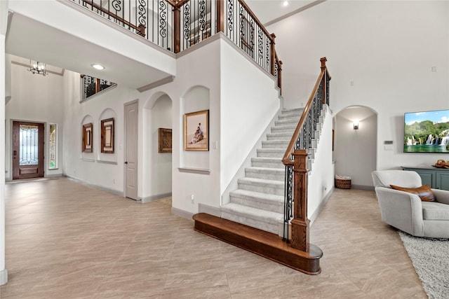 entrance foyer featuring a towering ceiling, baseboards, stairs, and arched walkways