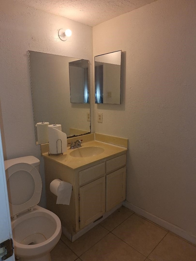 half bath featuring a textured ceiling, toilet, vanity, baseboards, and tile patterned floors