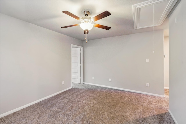 spare room with attic access, carpet floors, baseboards, and a ceiling fan