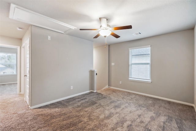 carpeted empty room featuring visible vents, baseboards, attic access, and a healthy amount of sunlight