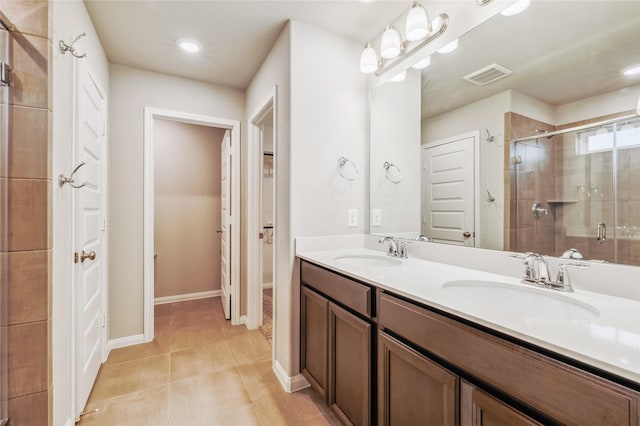 bathroom with double vanity, a stall shower, tile patterned flooring, and a sink