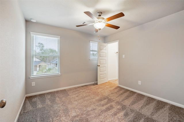 carpeted spare room featuring baseboards and a ceiling fan