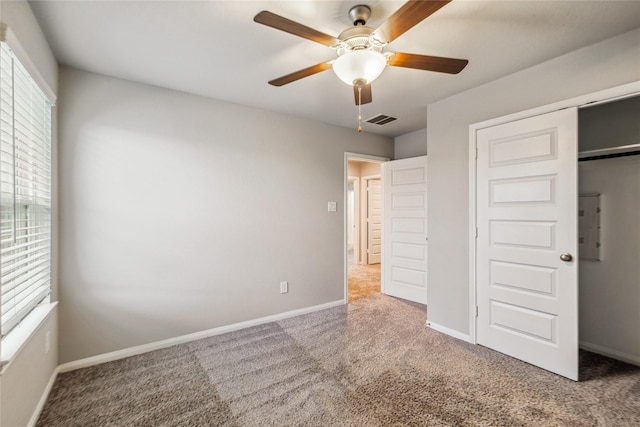 unfurnished bedroom featuring ceiling fan, visible vents, baseboards, electric panel, and carpet