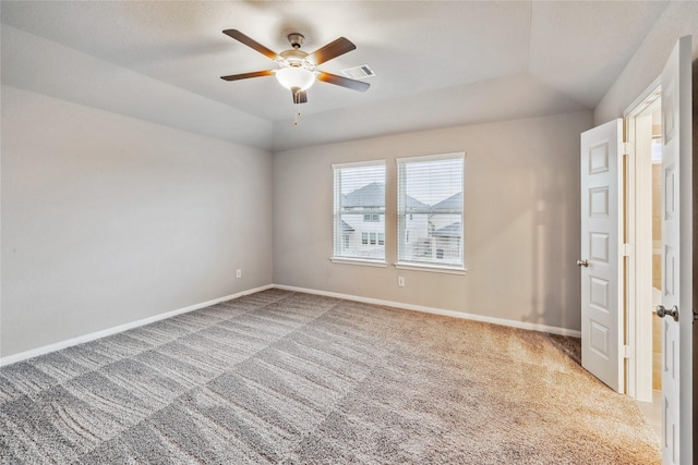 carpeted spare room with vaulted ceiling, a ceiling fan, visible vents, and baseboards