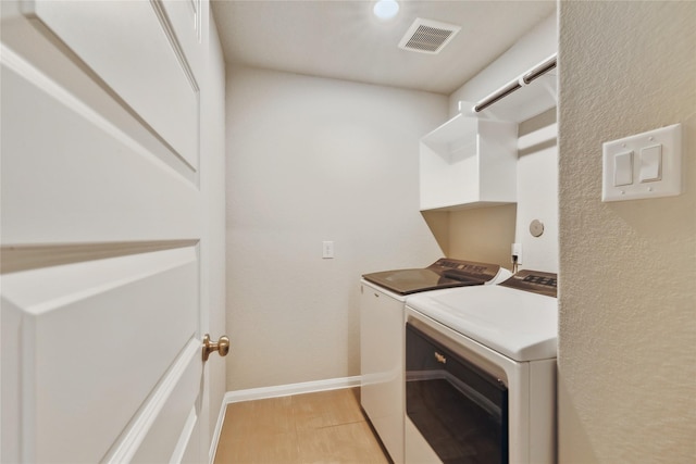 laundry area with laundry area, baseboards, visible vents, and separate washer and dryer