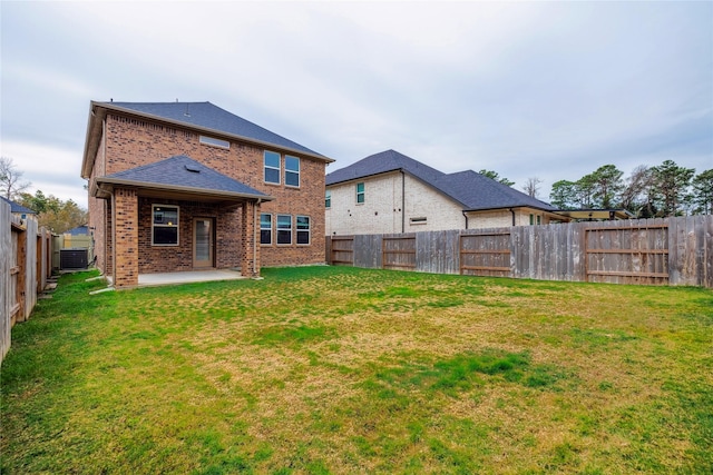 back of property with a patio, brick siding, a lawn, and a fenced backyard