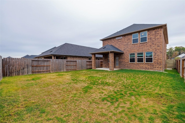 back of house with a fenced backyard, a patio, a lawn, and brick siding