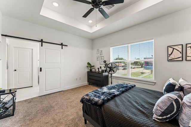 bedroom featuring recessed lighting, a raised ceiling, light colored carpet, and a barn door