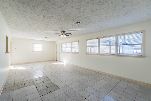 unfurnished room with visible vents, light tile patterned flooring, ceiling fan, a textured ceiling, and baseboards