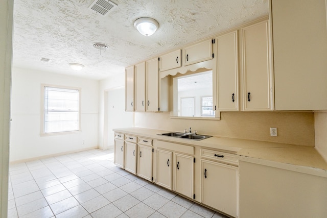 kitchen with light countertops, a sink, visible vents, and cream cabinets