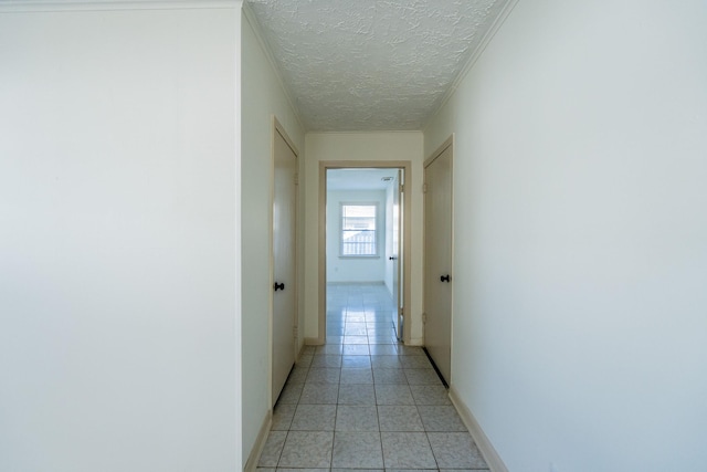 hall with a textured ceiling, light tile patterned floors, and baseboards