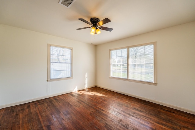 unfurnished room with dark wood-style floors, baseboards, visible vents, and a healthy amount of sunlight