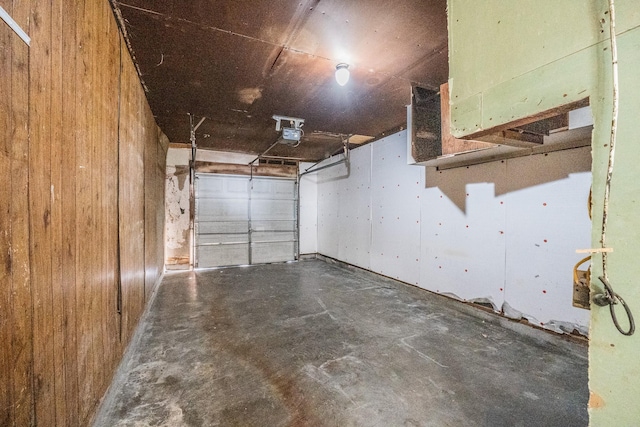 garage with wood walls and a garage door opener