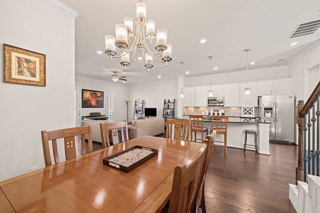 dining room featuring dark wood-style flooring, crown molding, visible vents, a ceiling fan, and stairs