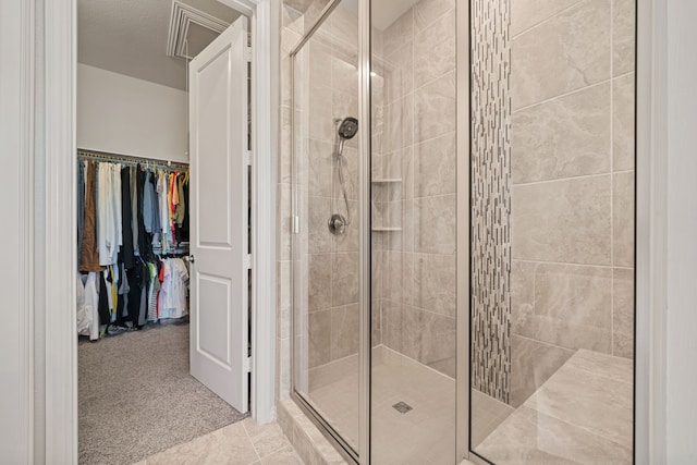 bathroom with a shower stall, a walk in closet, and tile patterned flooring