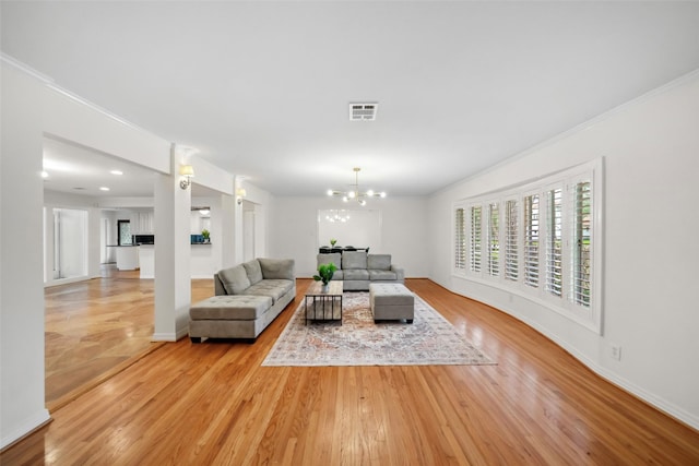 living area with a notable chandelier, visible vents, light wood-style flooring, ornamental molding, and baseboards