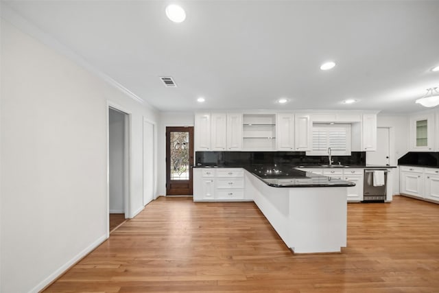 kitchen with a peninsula, visible vents, white cabinets, open shelves, and dark countertops