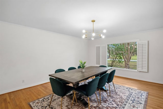 dining space with a chandelier, crown molding, baseboards, and wood finished floors