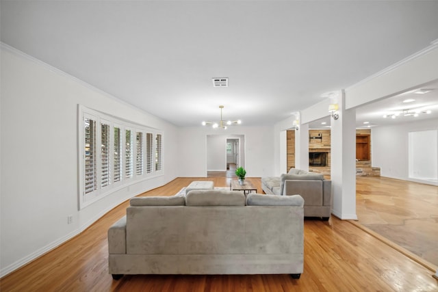 living area featuring a chandelier, visible vents, crown molding, and light wood-style flooring