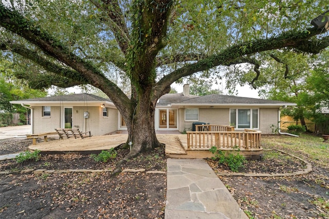 ranch-style house with a chimney, brick siding, and a deck