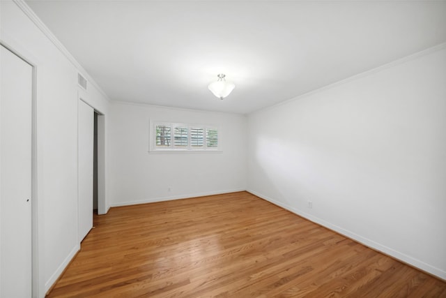 unfurnished bedroom featuring ornamental molding, light wood-type flooring, visible vents, and baseboards