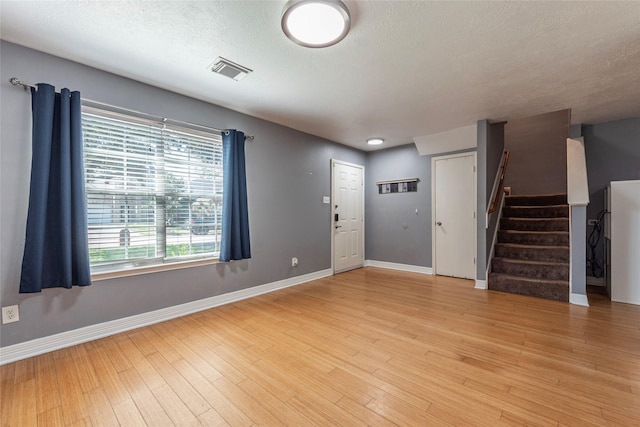 interior space with light wood-type flooring, stairway, baseboards, and visible vents