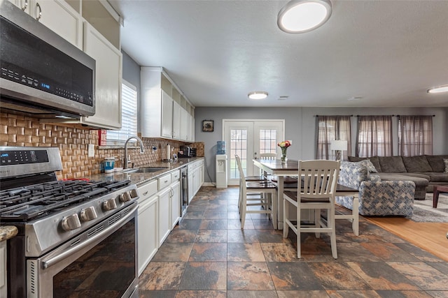 kitchen featuring tasteful backsplash, appliances with stainless steel finishes, plenty of natural light, and white cabinets