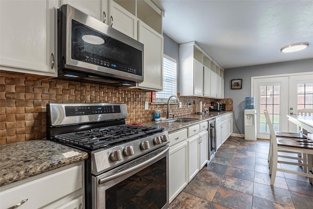 kitchen featuring appliances with stainless steel finishes, dark stone counters, and white cabinets