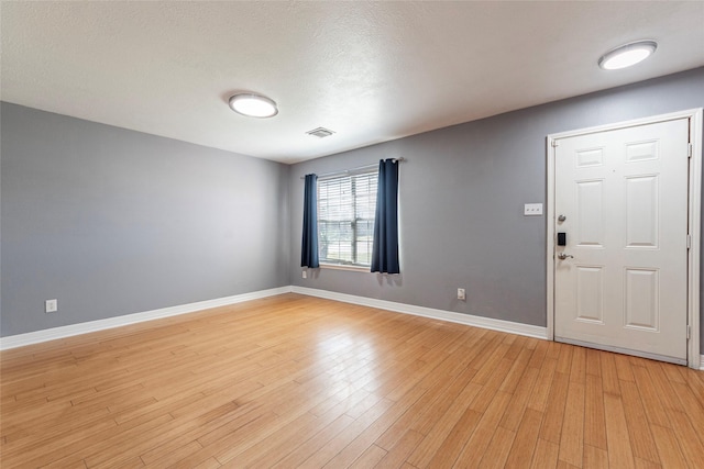 entryway featuring a textured ceiling, light wood-style flooring, visible vents, and baseboards