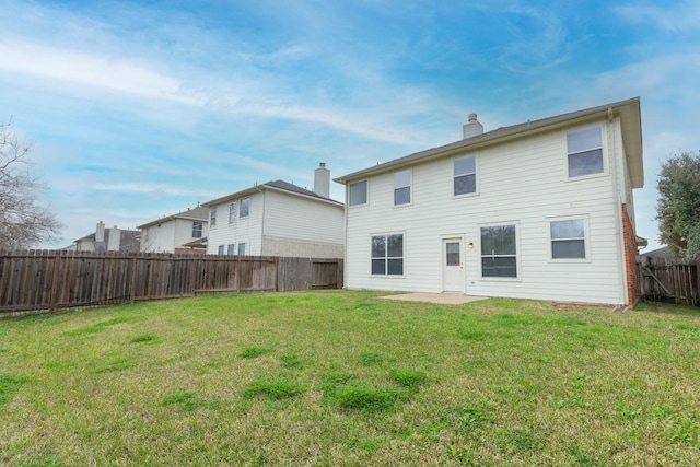 back of house featuring a fenced backyard, a chimney, and a lawn