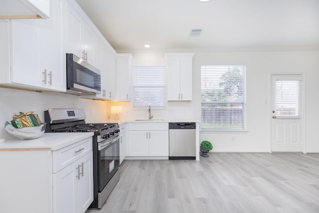 kitchen featuring stainless steel appliances, light countertops, visible vents, white cabinets, and a sink