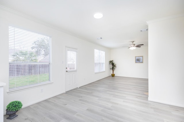 empty room featuring light wood-type flooring, ceiling fan, visible vents, and ornamental molding