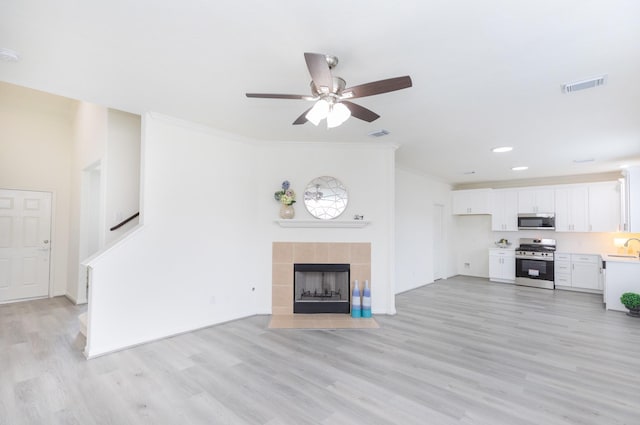 unfurnished living room featuring light wood finished floors, a fireplace, visible vents, and ornamental molding