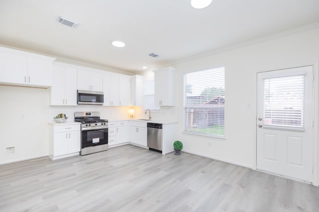 kitchen with appliances with stainless steel finishes, light countertops, a sink, and white cabinetry