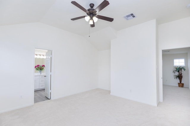 spare room with light colored carpet, lofted ceiling, visible vents, and ceiling fan