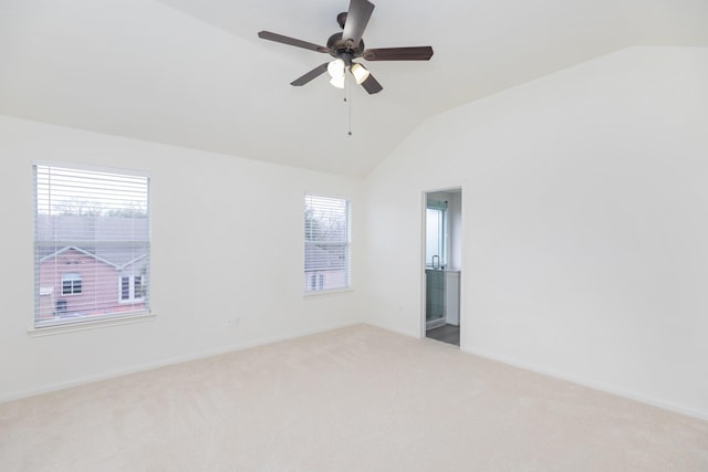 carpeted spare room featuring vaulted ceiling, baseboards, and ceiling fan