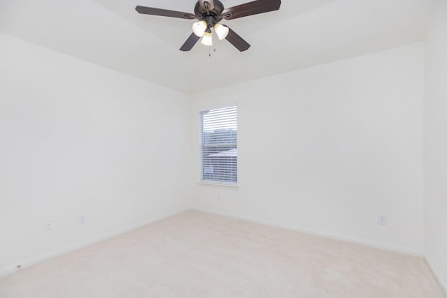 spare room featuring light carpet, ceiling fan, and baseboards