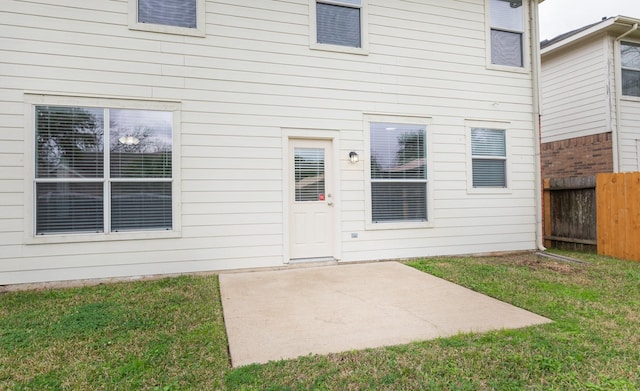 property entrance featuring a yard, fence, and a patio