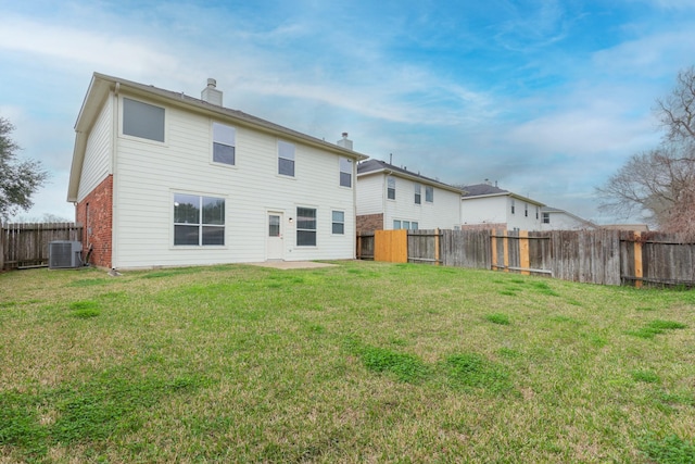 back of property featuring a chimney, central AC, a lawn, and a fenced backyard